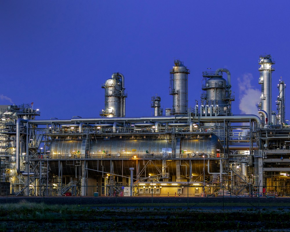 A petrochemical refinery lit at dusk — the plant assets AI keeps running