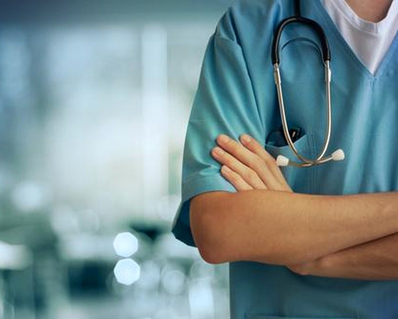 A clinician with a stethoscope — ambient AI drafts the note so the clinician stays in charge