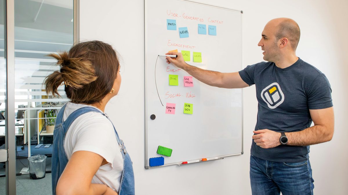 Two colleagues mapping ideas on a whiteboard with sticky notes — identifying candidate use cases