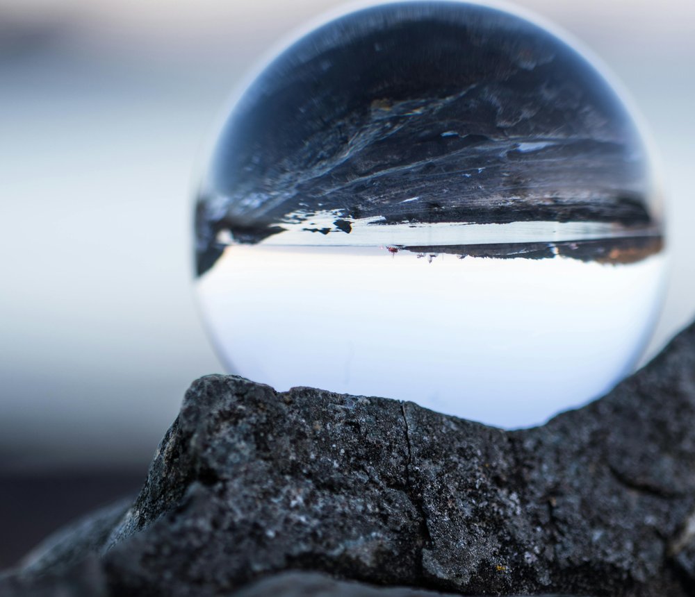 A glass sphere resting on volcanic rock, inverting the landscape seen through it